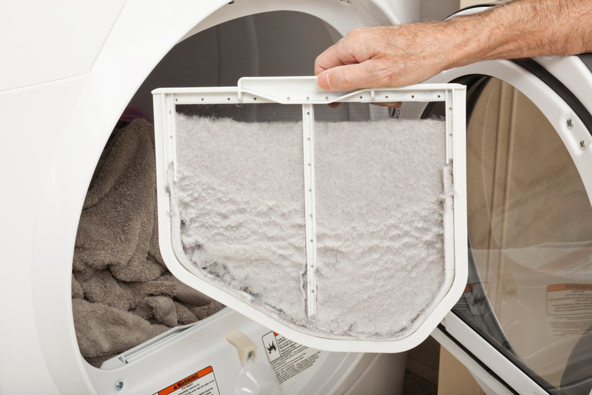 Hand holding a clothes dryer lint filter that is covered with lint.