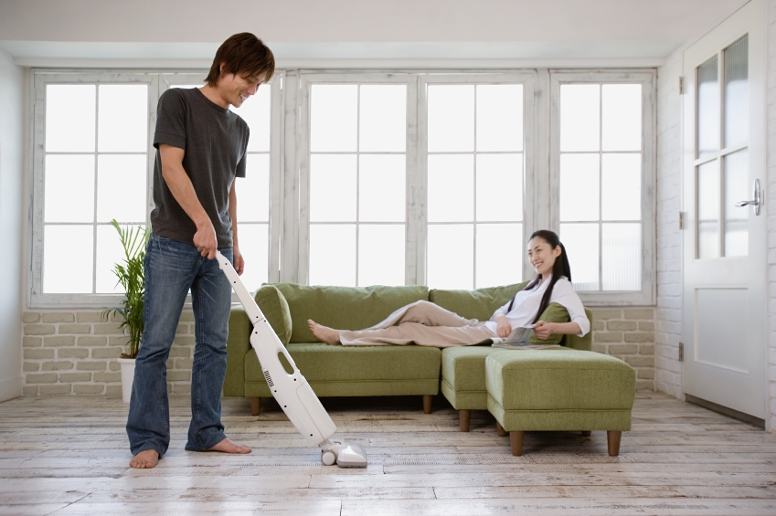 Man vacuuming and woman on sofa