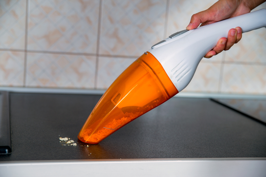 The female hand holds a portable vacuum cleaner